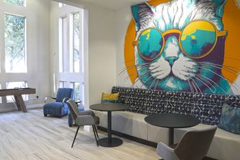A room with a cat mural on the wall and a table with chairs.